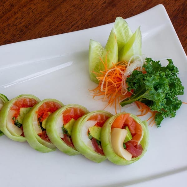 Thai West's fresh cucumber-wrapped sushi rolls with salmon, tuna, avocado, and roe, garnished with kale and carrots.
