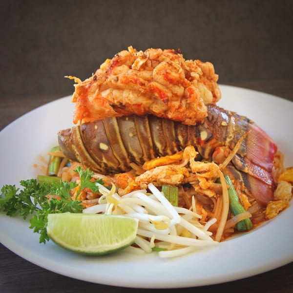 Thai West's Pad Thai with a whole lobster, garnished with lime, bean sprouts, and parsley.